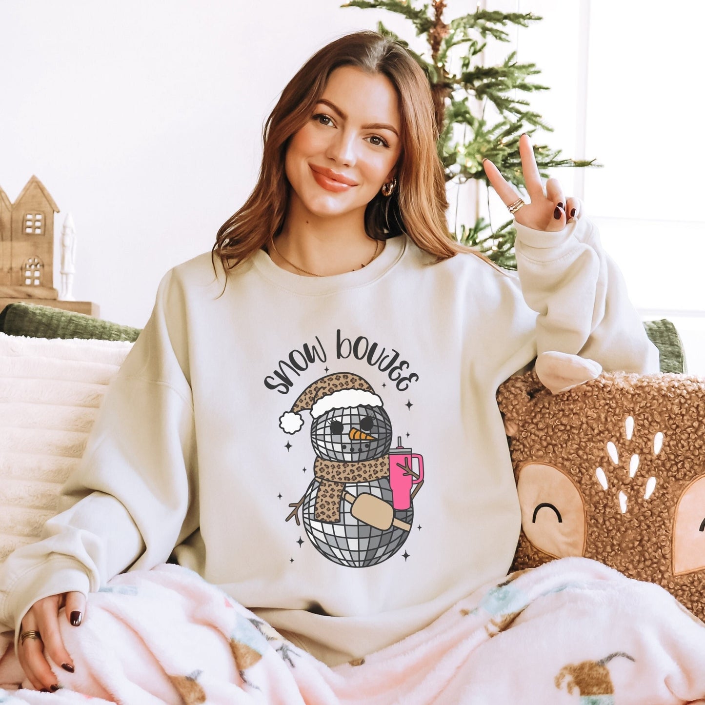 Snow Boujee disco ball snowman with leopard santa hat, leopard scarf, neutral buckle bag and a large pink water cup on an oversized sweatshirt