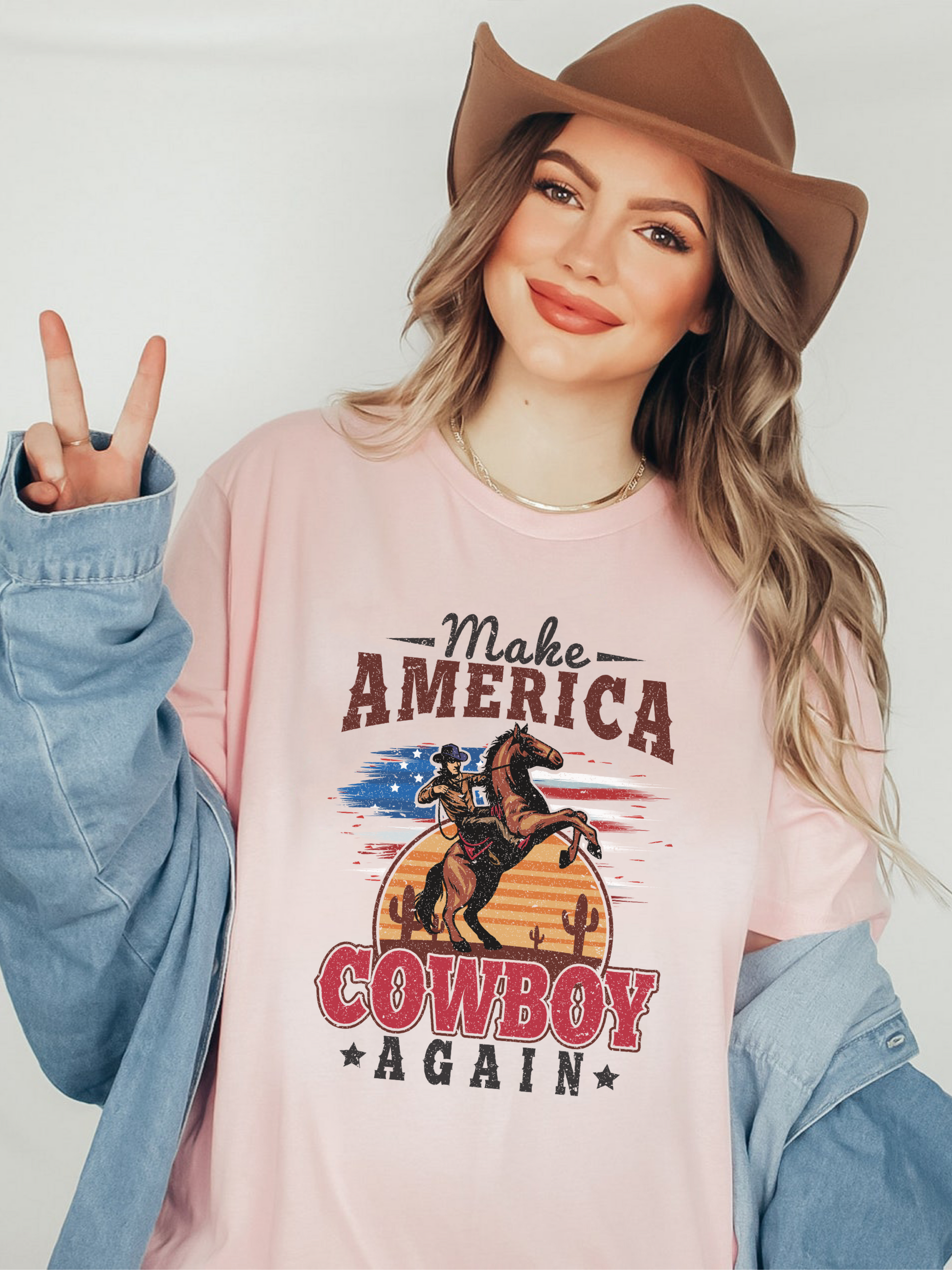 Model wearing soft pink bella canvas tshirt with distressed western make america cowboy again print