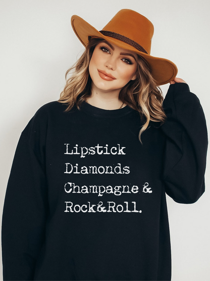 Model wearing black crewneck with distressed rock and roll, champagne, lipstick and diamonds graphic